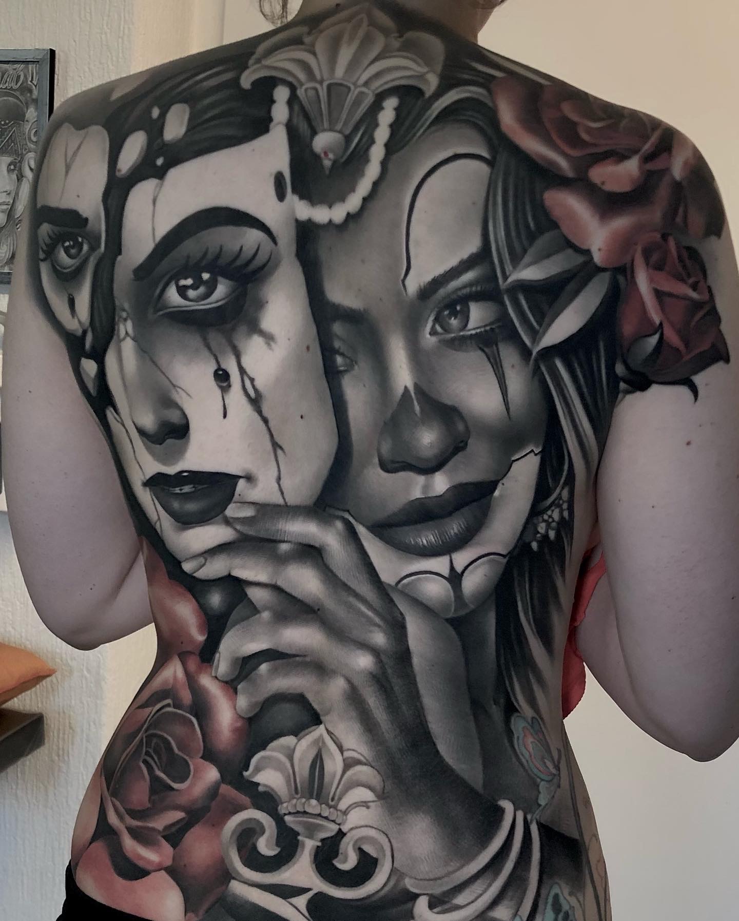 Farbiges Realismus-Tattoo mit zwei Gesichtern und Rosen auf dem Rücken