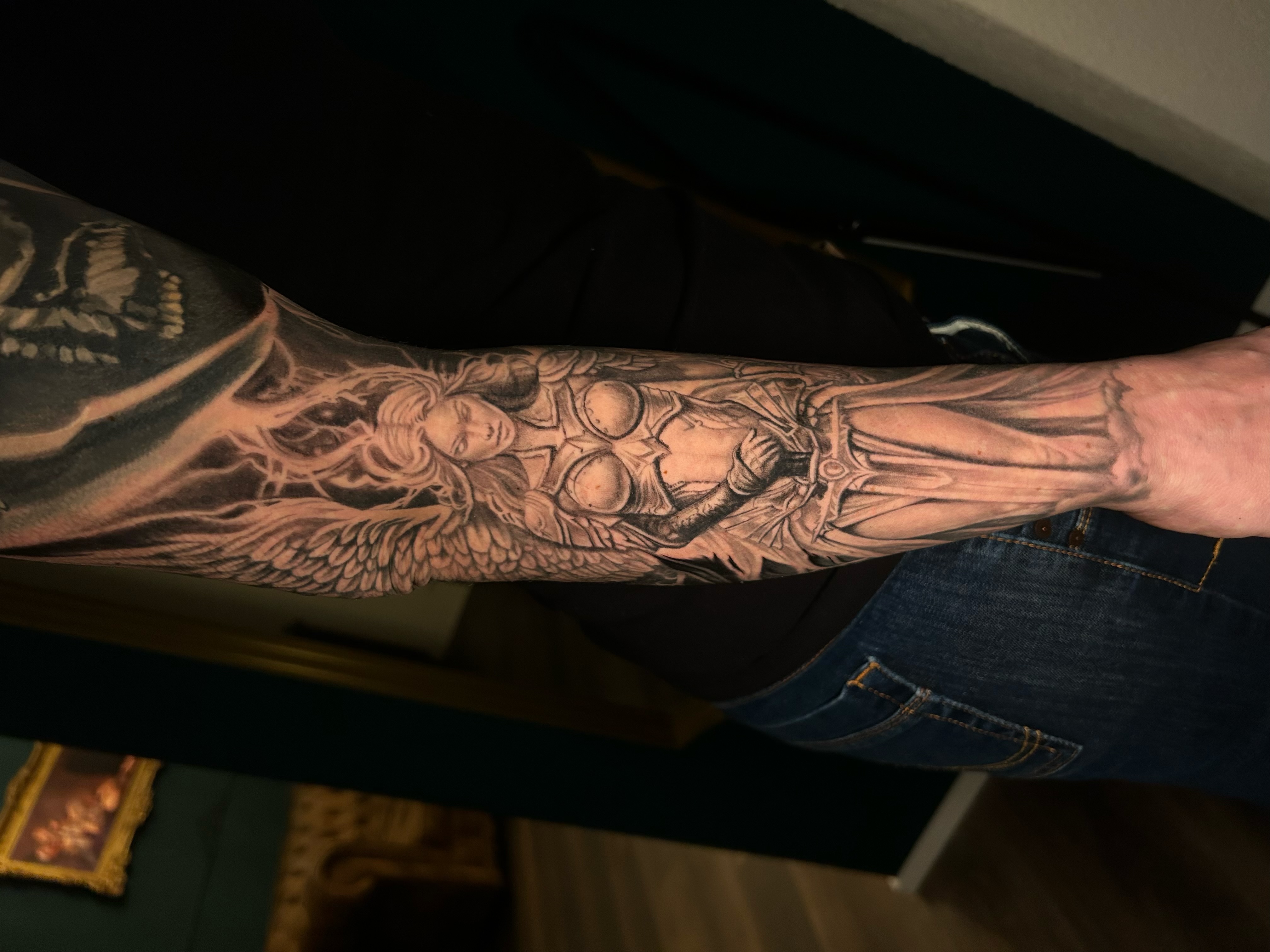 Black & Grey Tattoo mit geflügelter Rüstungsfigur am Unterarm