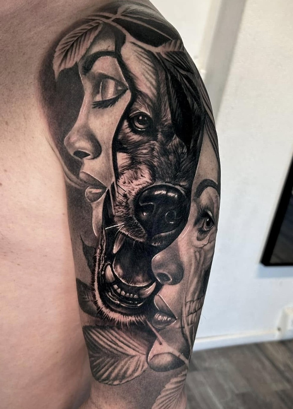 Cover-up nachher: aufwendiges Black & Grey Realismus-Motiv mit Frauenportrait, Wolf und Totenkopf am Oberarm