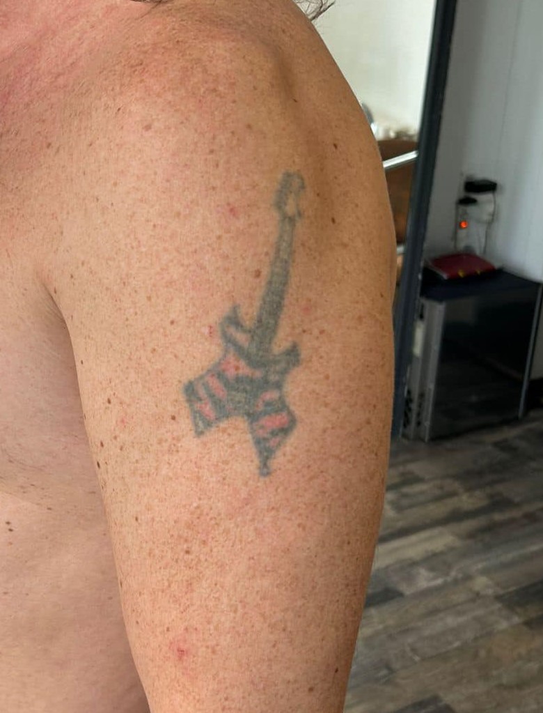 Cover-up vorher: verblasstes, kleines Gitarren-Tattoo am selben Oberarm